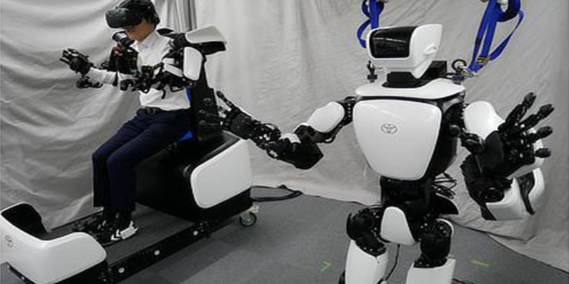 A person controlling the humanoid robot, T HR3, through a VR headset, wearable devices and seated controller.