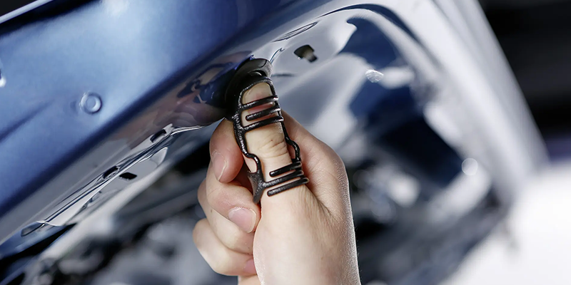 A person wearing the paxeo thumb exoskeleton around their thumb as they press their thumb against a machine like surface.