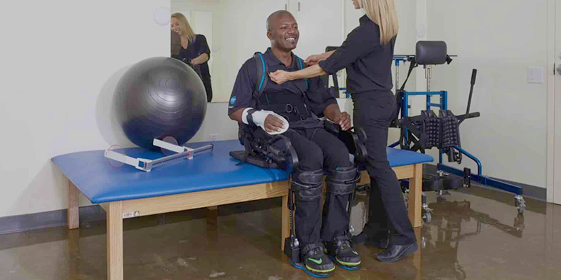 A person wearing the EskoNR on their legs as a Physical Therapist assists them.