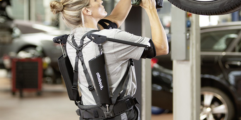 A person wearing the Ottoback exoskeleton as they work overhead on a car.